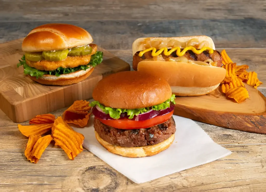 A plate of Cheesy Chicken Sloppy Joes served on soft hamburger buns, garnished with pickles and chopped green onions, alongside a side of sweet potato fries.