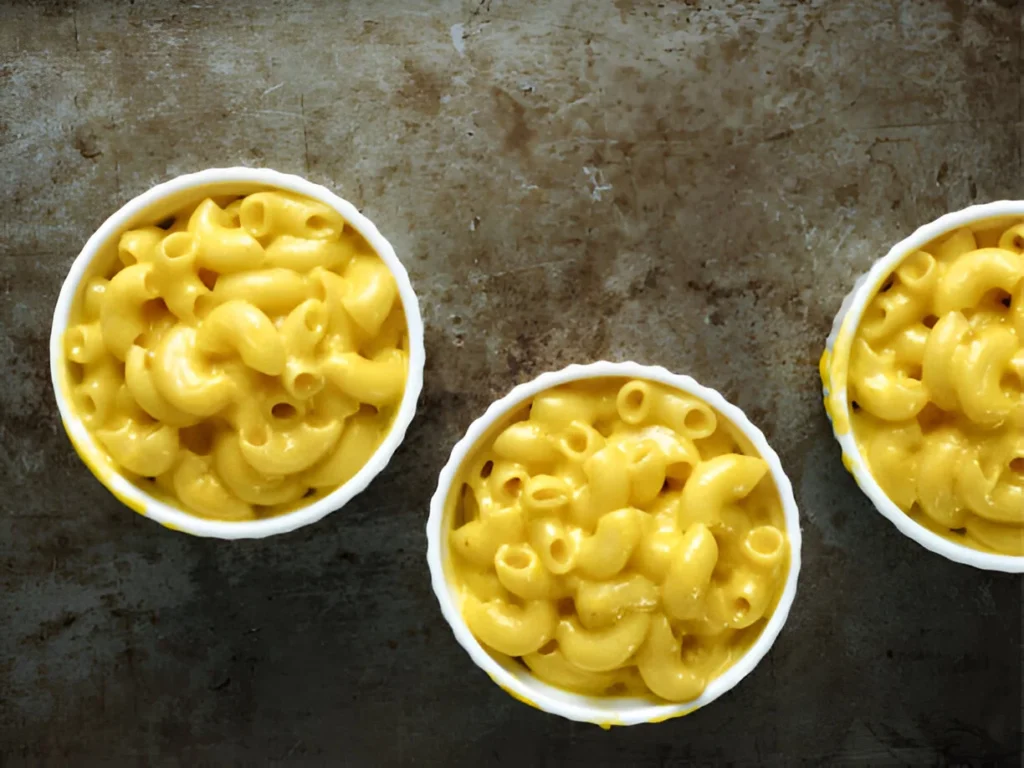 A creamy bowl of Tin's Mac and Cheese topped with a golden crispy breadcrumb layer, garnished with parsley.