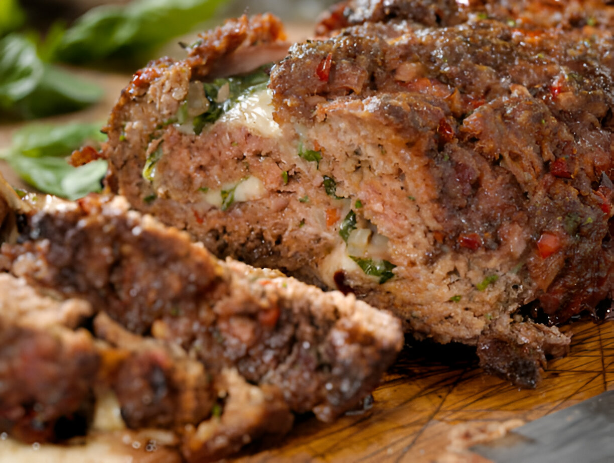 A delicious Italian meatloaf served on a plate, garnished with fresh herbs and accompanied by a side of marinara sauce, showcasing its rich, savory texture.